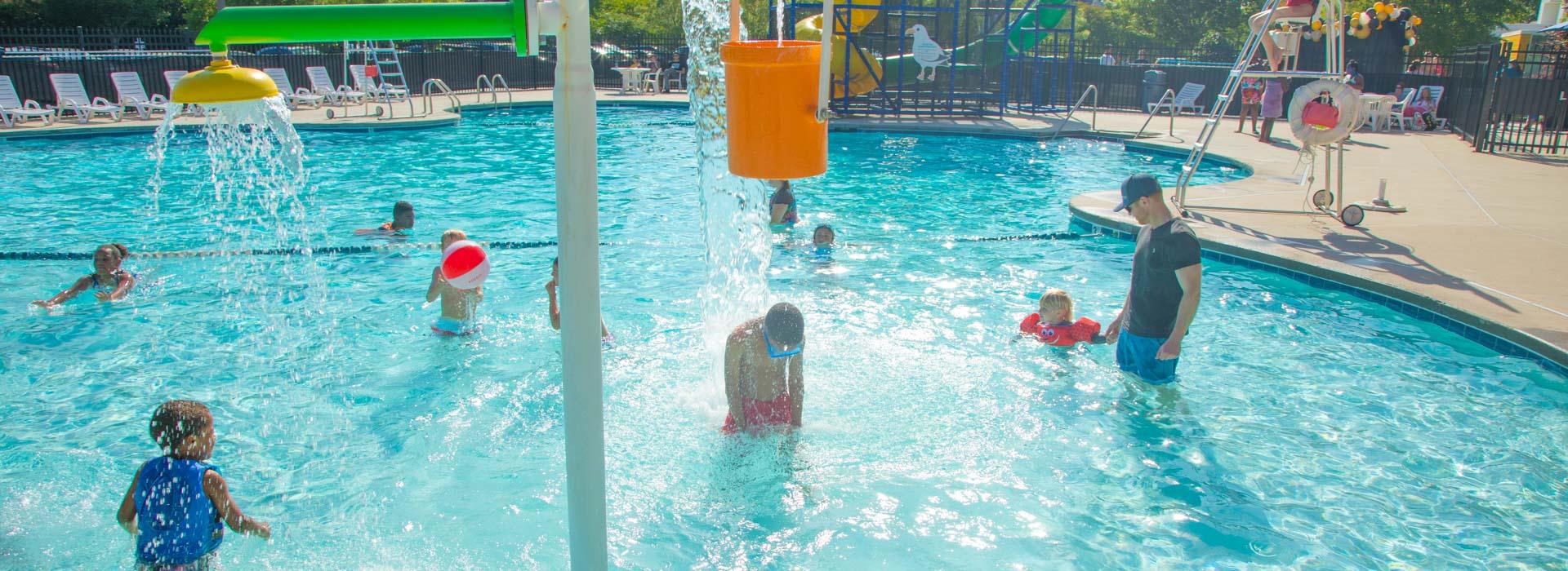 Children splash and play under the splash buckets in the pool at the YMCA on Granby