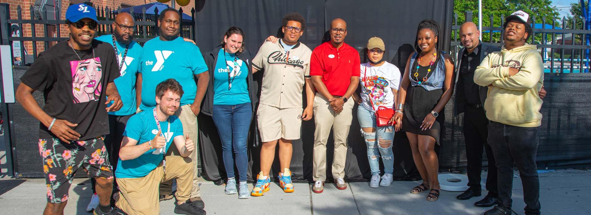 A group of members and staff stand in front of the celebration photo backdrop at the YMCA on Granby's 10th year anniversary