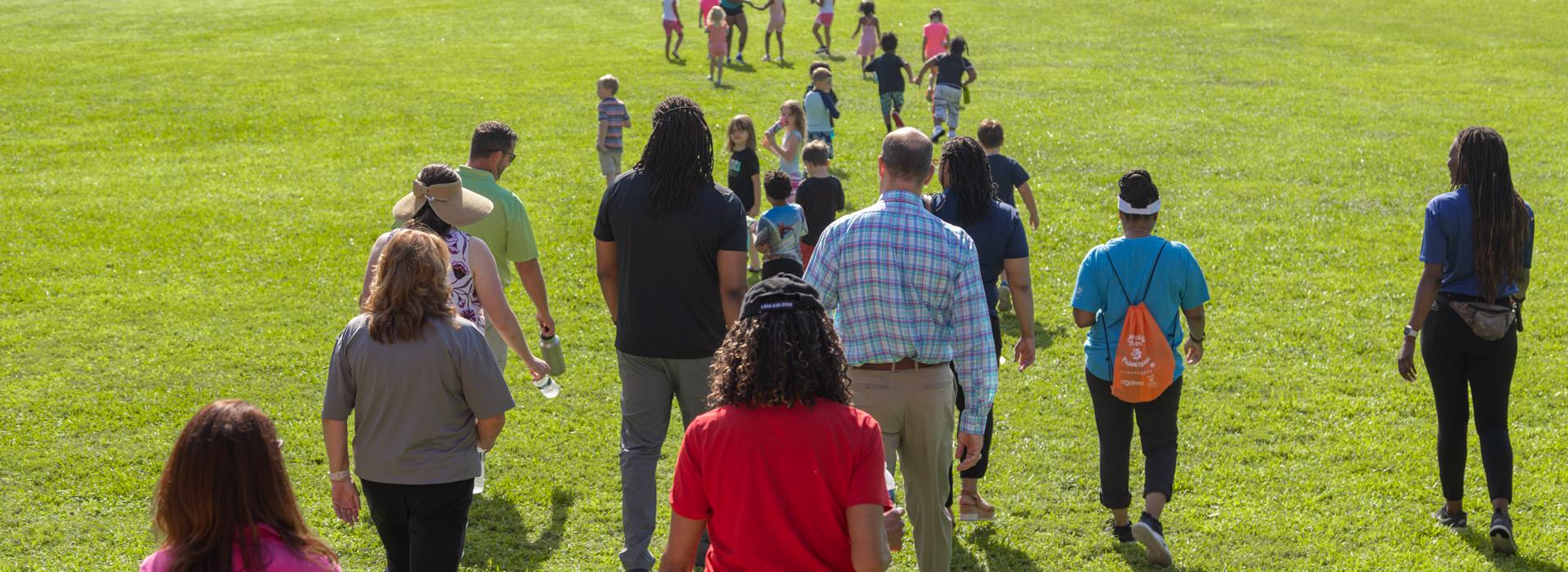 Camp donors walk across YMCA Camp Red Feather's fields to meet campers