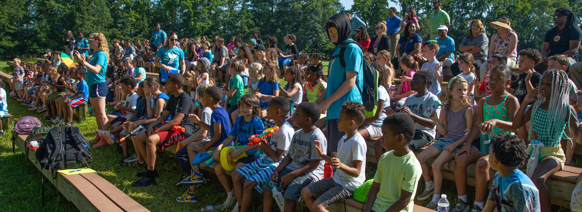 Campers sit in the amphitheater during YMCA Camp Arrowhead opening ceremony