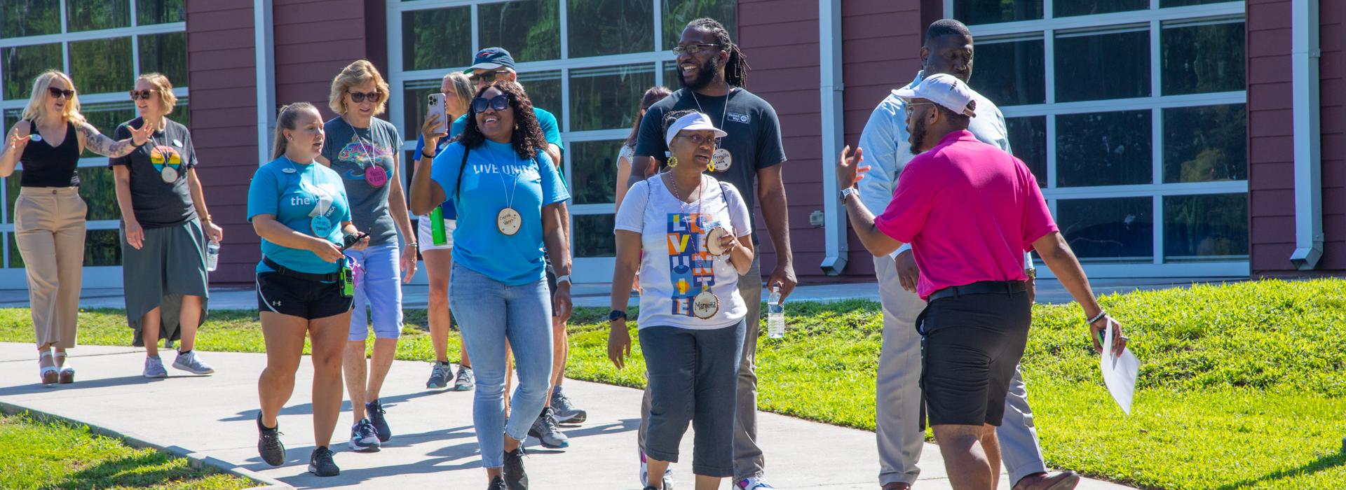 YMCA staff and donors have conversation while walking outside at YMCA at JT's Camp Grom