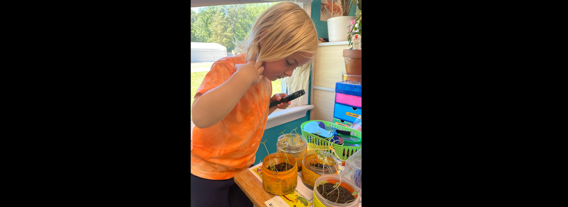 A kid at the Salem YMCA Family Center looking through a magnifying glass at plants