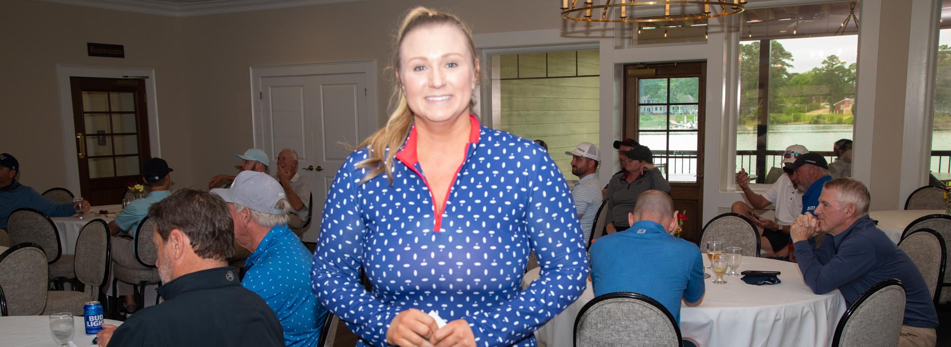 Woman in blue shirt smiles at the camera after winning an award