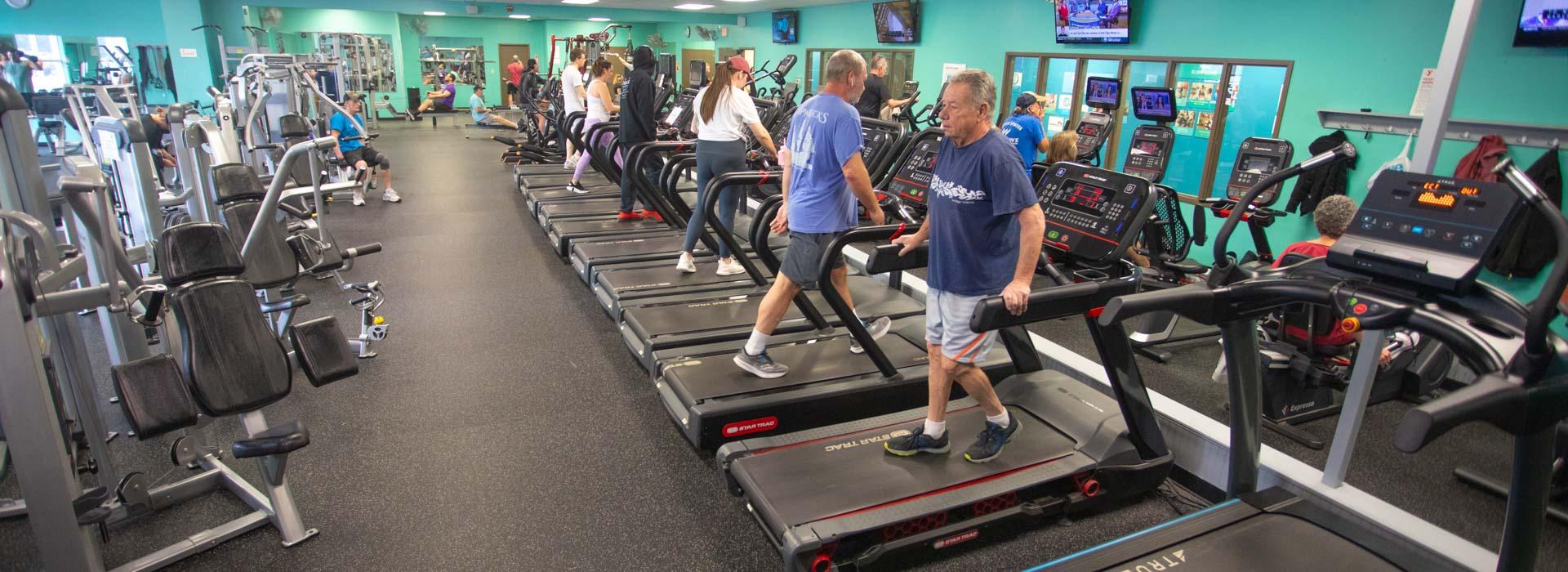 Wellness fitness center with people on treadmills and workout machines at the Outer Banks Family YMCA