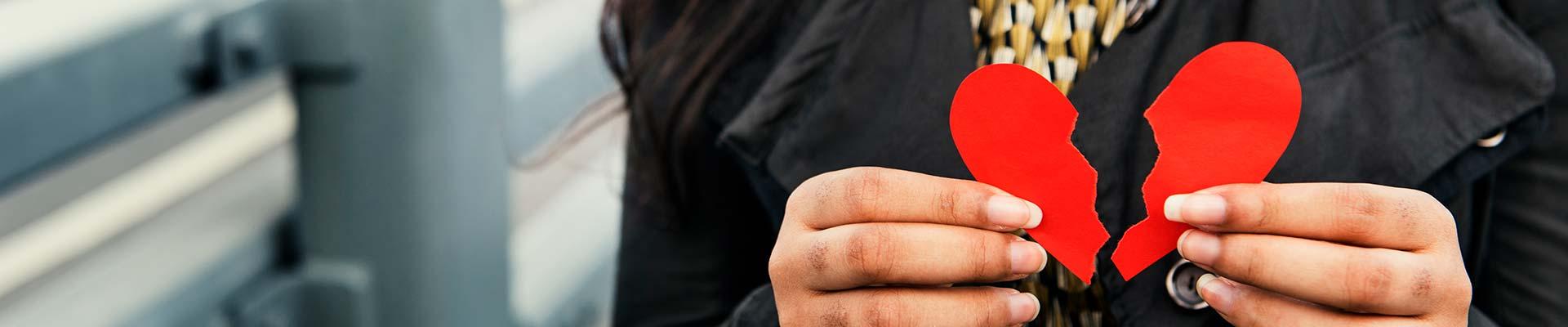 Hands holding a broken paper heart