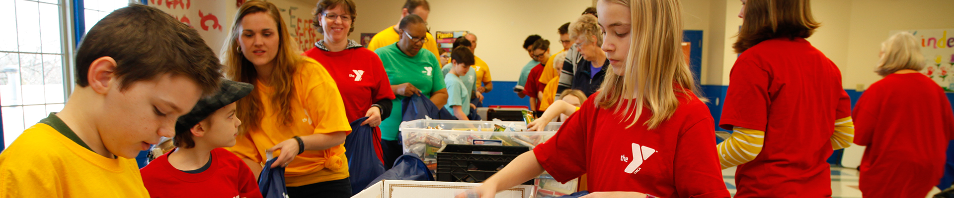 YMCA Togetherhood® volunteers stuffing bags with school supplies