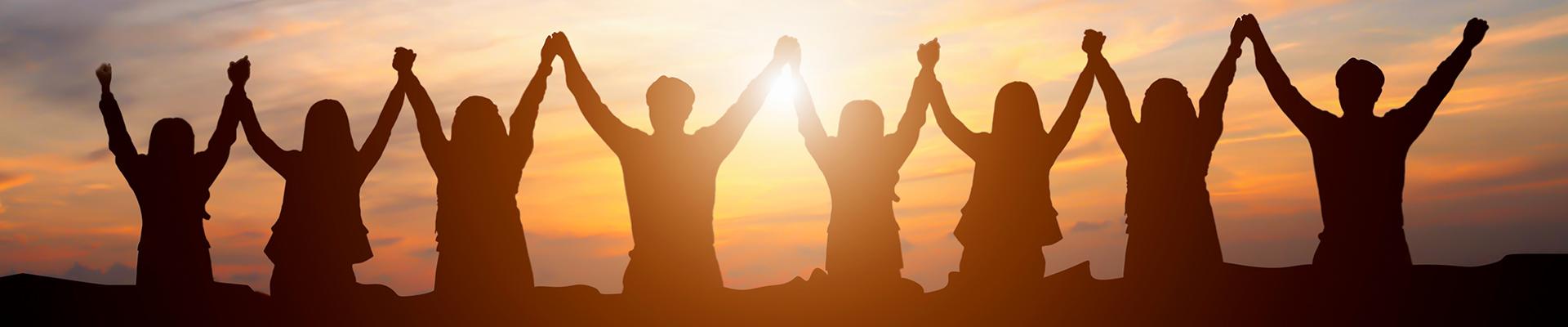 Silhouette group of people raising held hands in unity