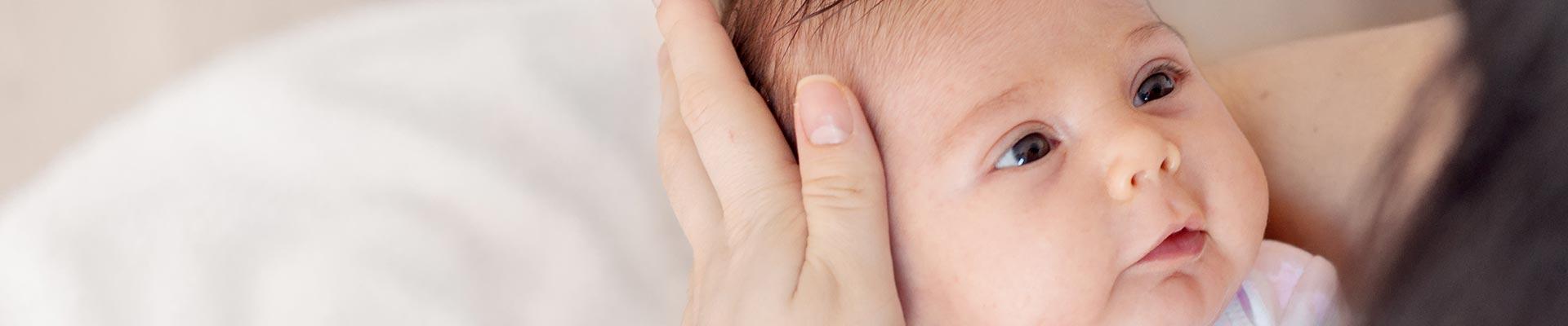 Baby looking up at mother, her hand on the side of baby's face