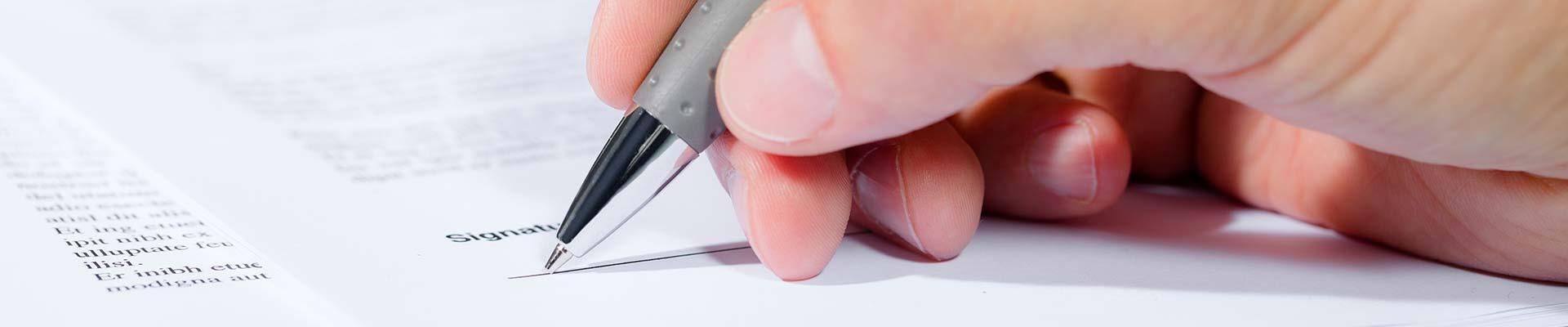 Hand and pen signing an agreement
