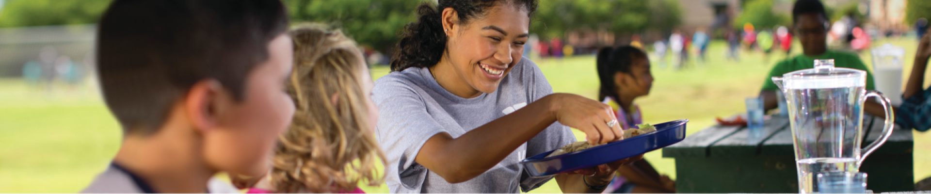 Camp counselor smiling while preparing snack for s summer campers