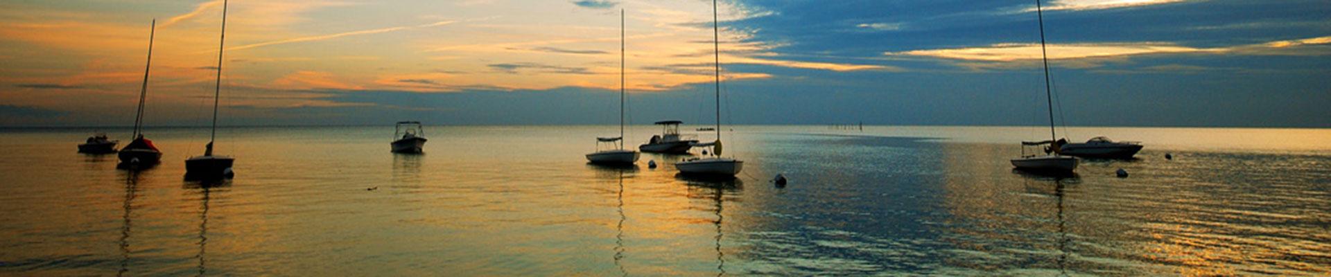 YMCA Camp Silver Beach sailboats resting on the still Chesapeake Bay at sunset, sails down
