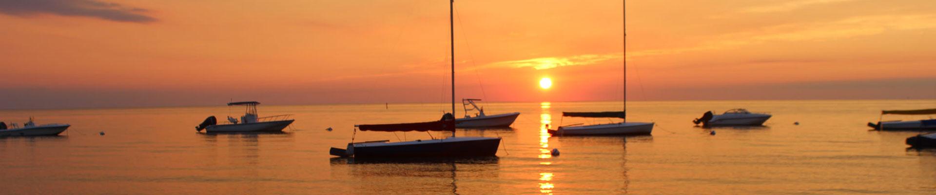 Orange sunset over Chesapeake Bay with sailboats in the water at YMCA Camp Silver Beach