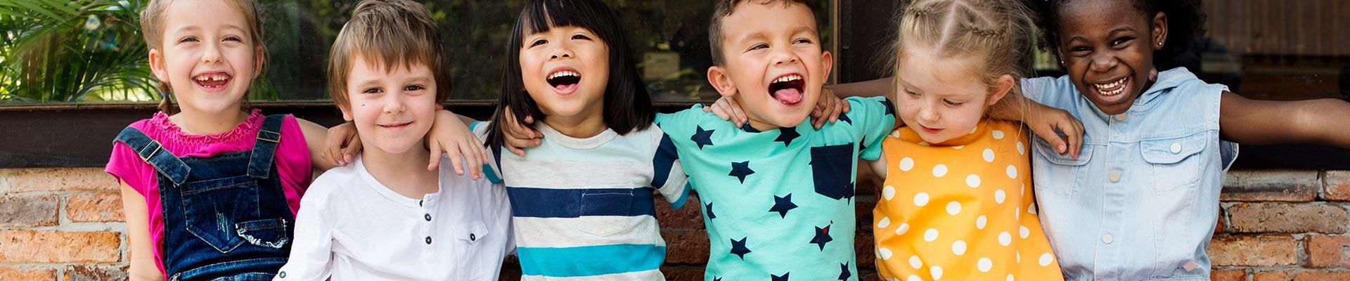 Row of young children laughing with arms around each other