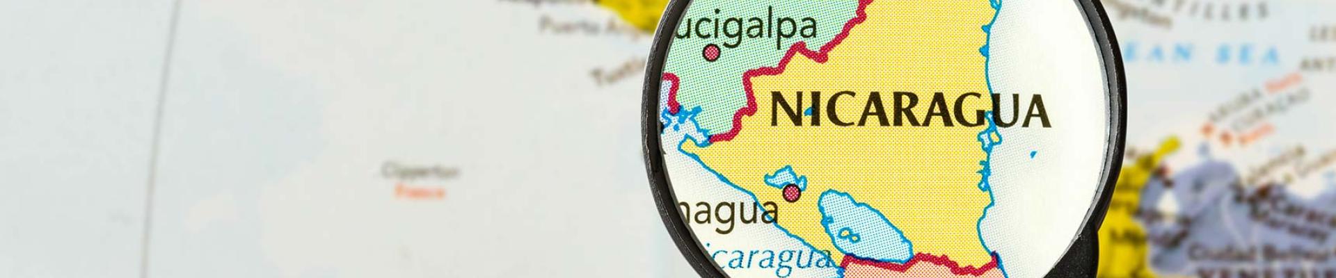 Using a magnifying glass to look at Nicaragua on a map