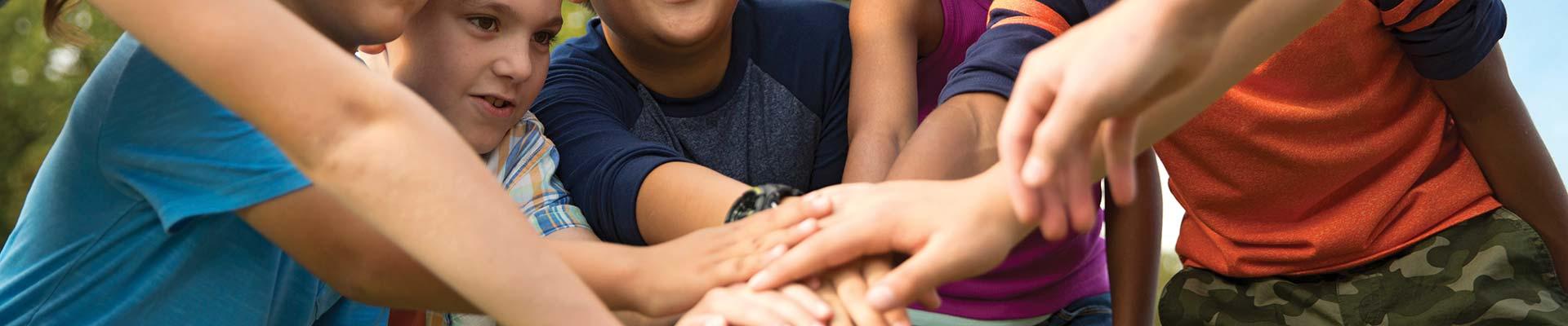 A group of campers putting hands together in teamwork