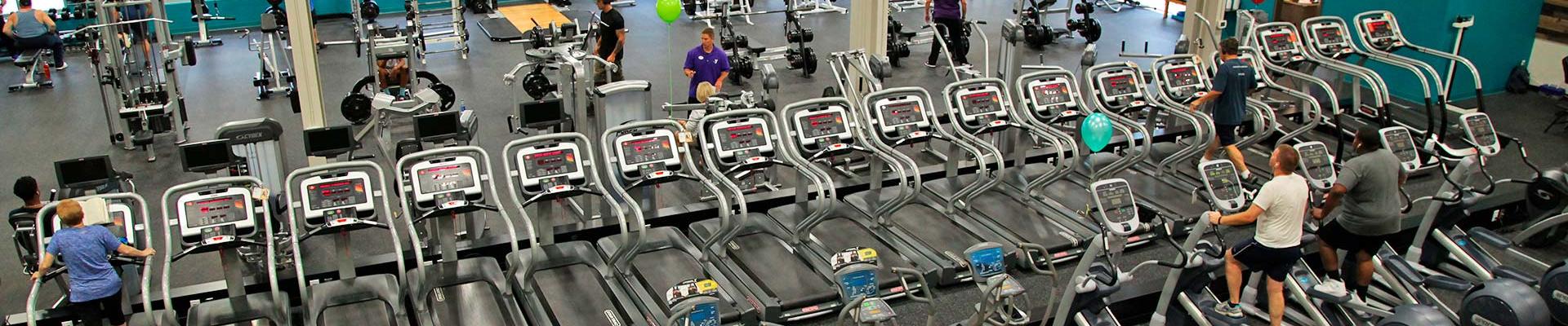Looking down on the YMCA fitness center from above, seeing elliptical machines, treadmills, and free weight center with a few members using the equipment to work out