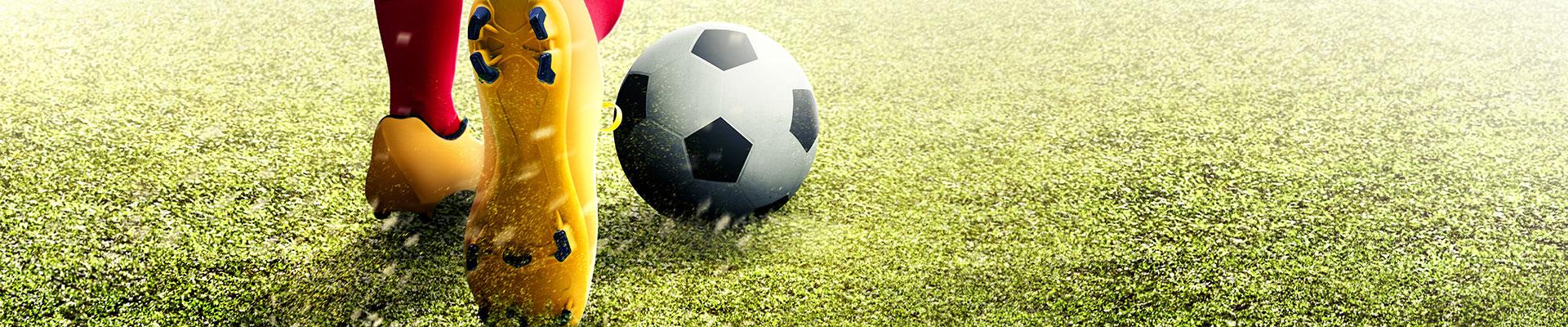 Cleaated feet and soccer ball on turf