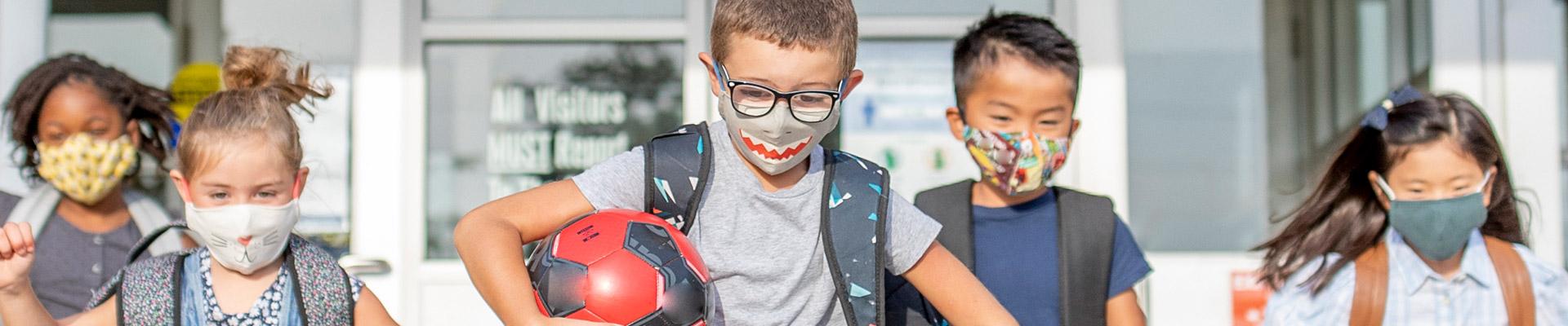5 children with cloth masks running and laughing