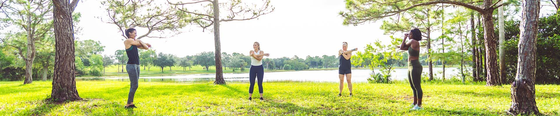 Outdoor fitness class where participants are distanced and stretching