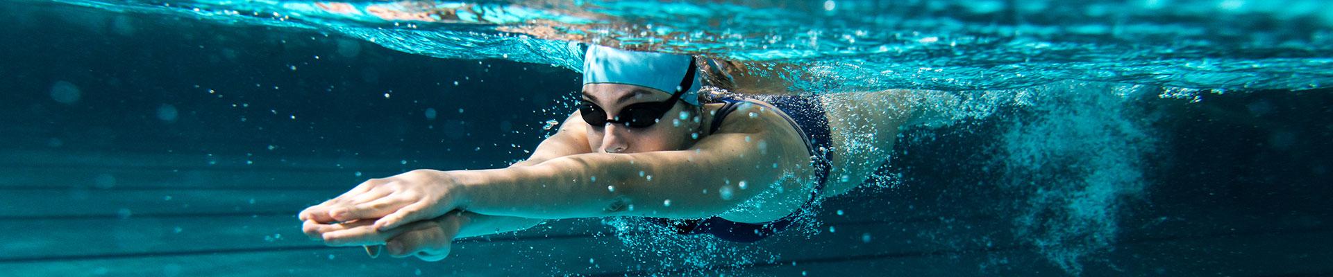 Female adult swimmer gliding away from the wall under water while swimming laps
