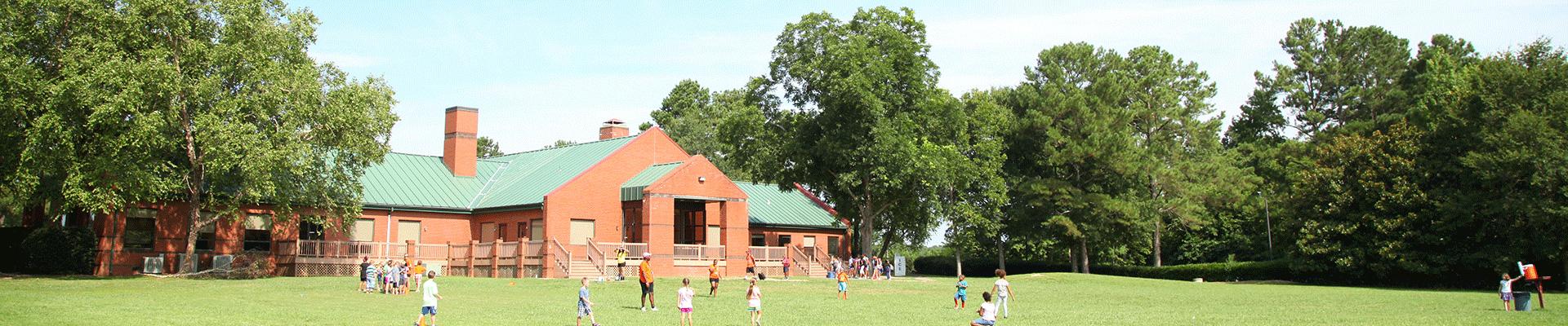 Outdoor shot fo summer campers playing in the field behind Camp Arrowhead's main building