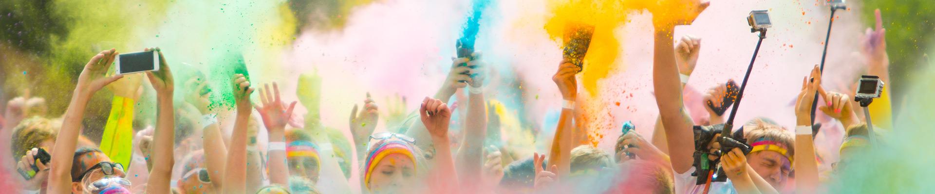 crowd of runners taking selfies while throwing color powder during a color run