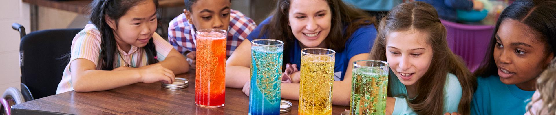 A diverse group of children in after-school care work on a science experiment.