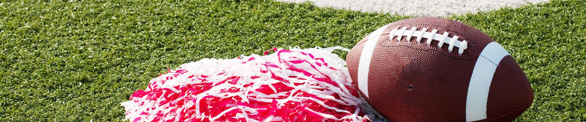 Grass field with football and red and white pom pom