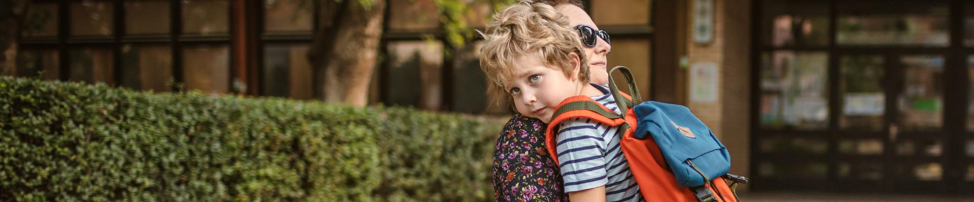 A child hugs mom goodby outside preschool