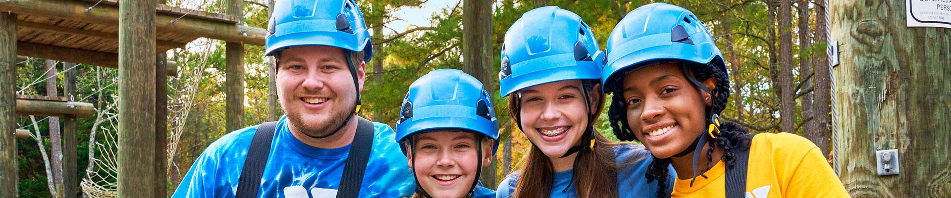 Teen leaders and staff advisor prepare to biplane through an adventure park