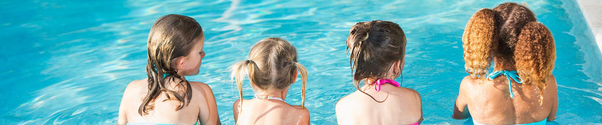 Four girls sitting in the pool at the Y, looking at the water and chatting