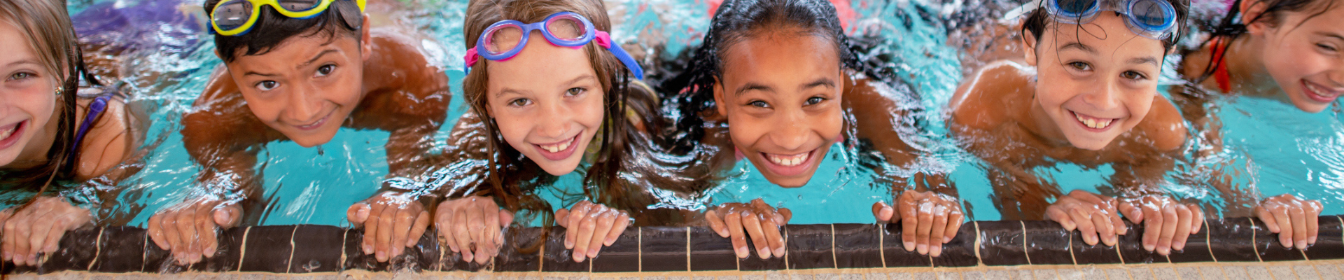 children on the side of the pool in the water