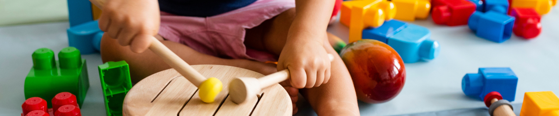 Child playing with drum with legos around them