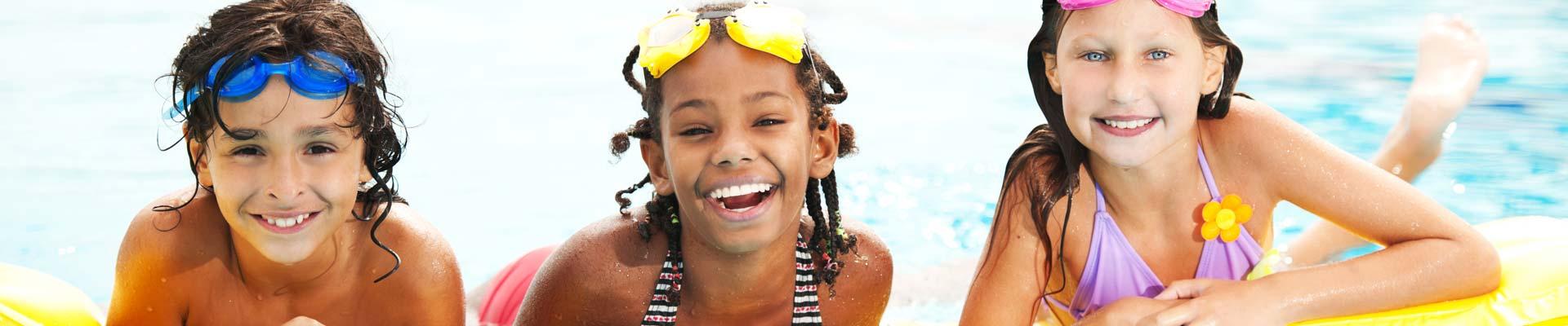 Three tween campers laughing in swimming pool