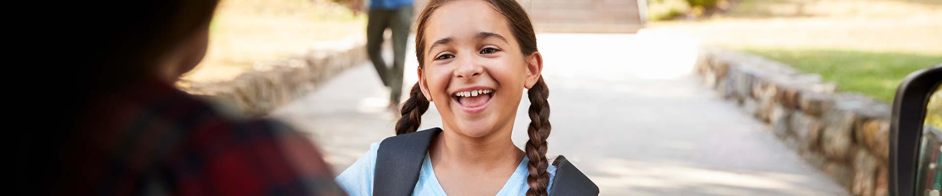 A young girl's face lights up as she sees her mom at the end of a fun day at camp.