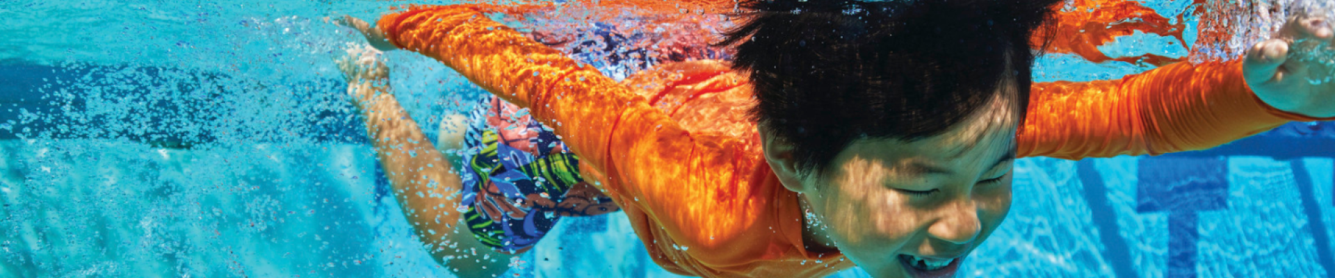 A small boy swims underwater for his swim lessons