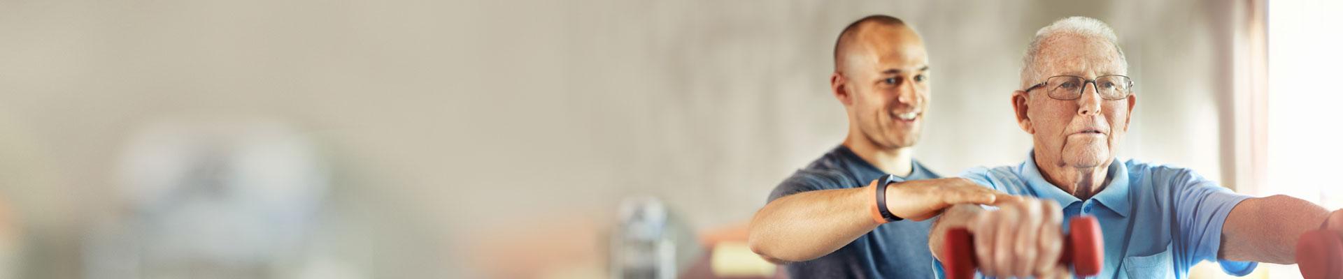 Personal trainer helping correct form for senior lifting dumbbells