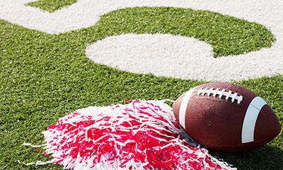 Grass field with football and red and white pom pom