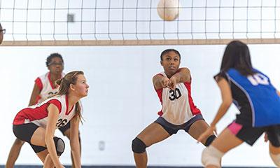 Group of girls actively playing volleyball