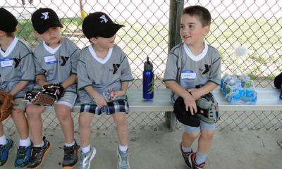 T-ball team sits on the bench in the dugout area