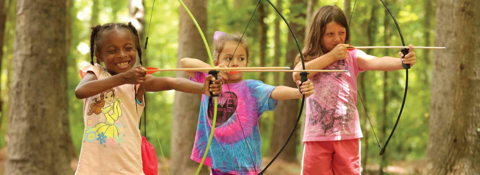 Three female campers shooting arrows at targets