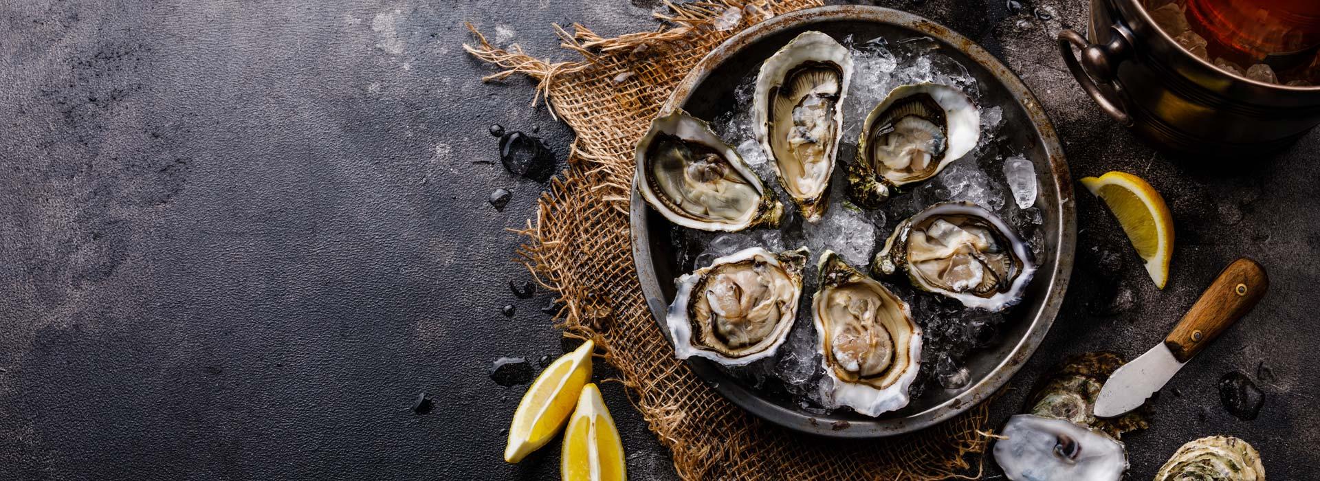 Six roasted oysters on ice, with lemons and oyster knife