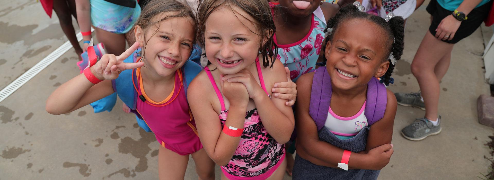 Group of summer campers on the swimming pool deck smiling at the camera