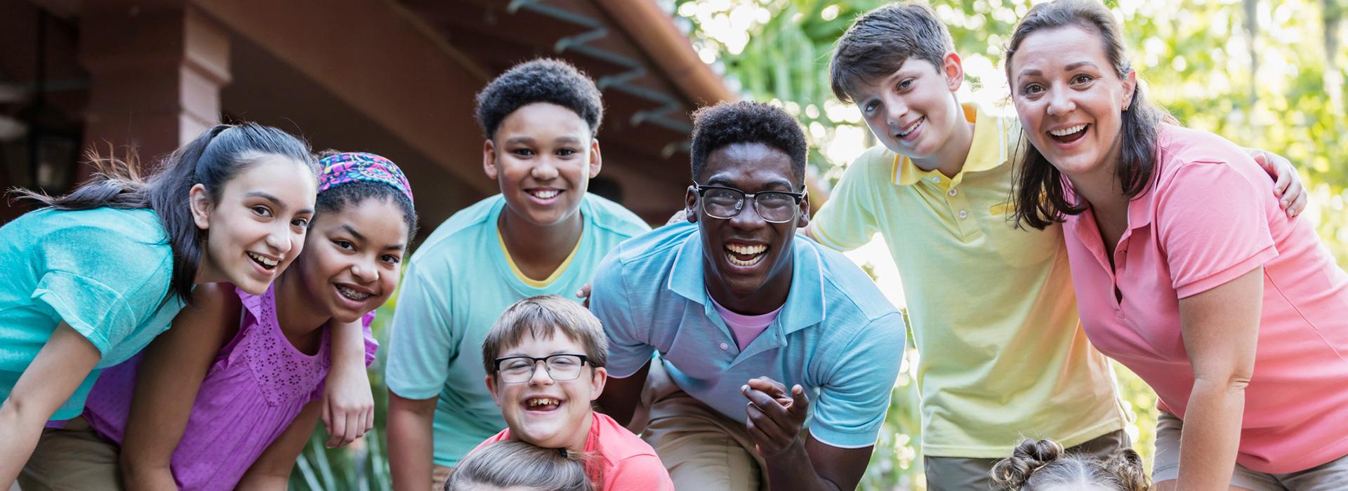 Summer camp counselors with a group of campers, smiling and having fun while looking at the camera