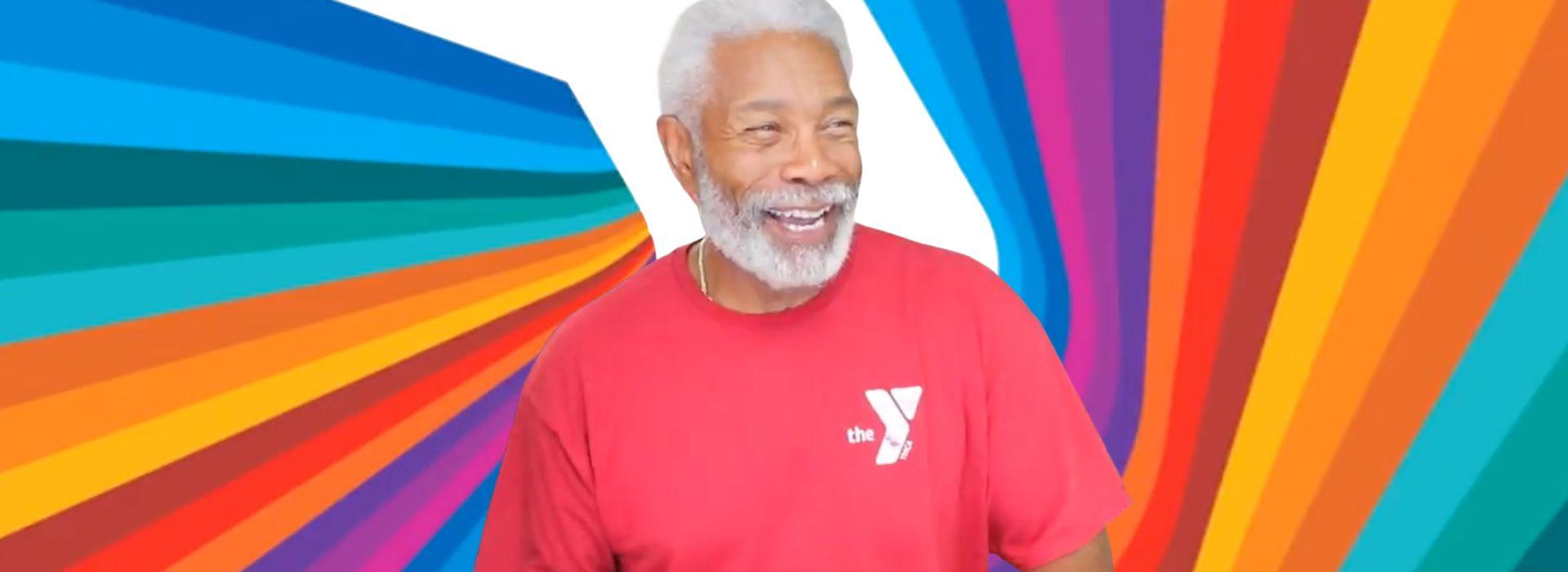Colorful dynamic background with older gentleman in red shirt with Y logo, looking slightly off to the right and smiling