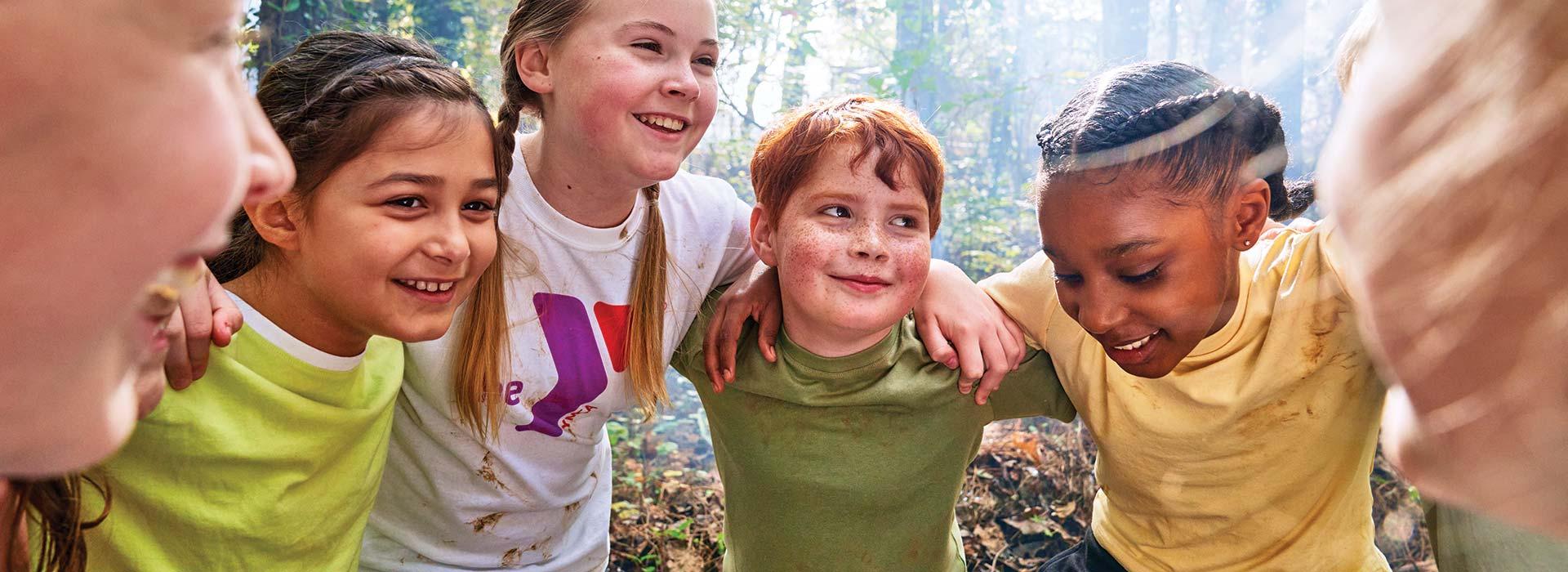 Group of summer campers in huddle smiling and having fun outside