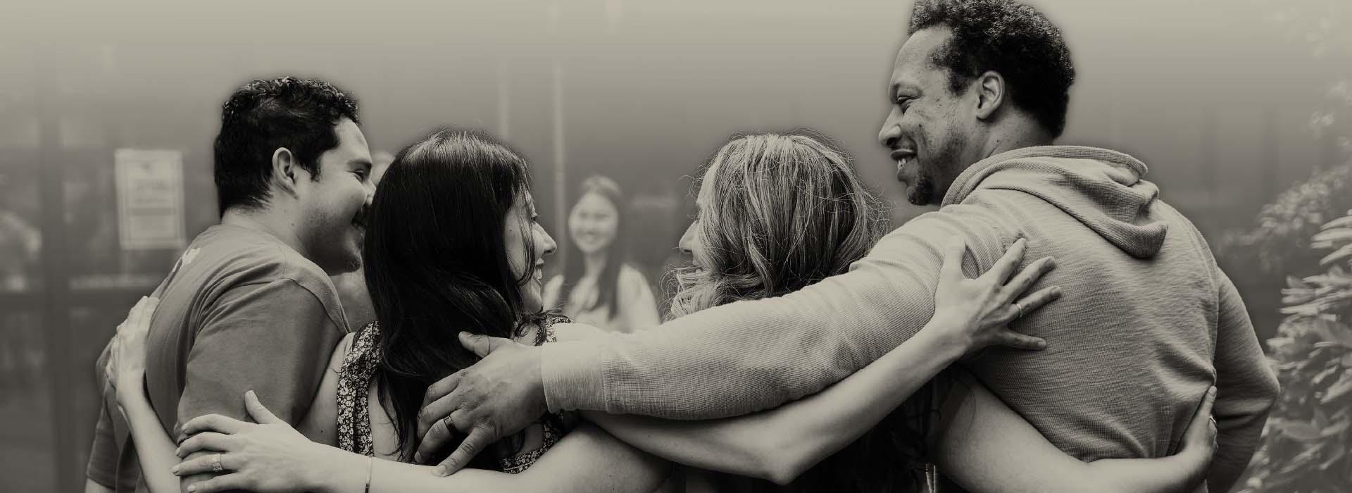 Group of peopel smiling at each other with their arms around each other.