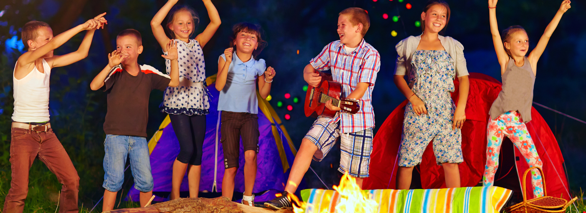 Kids having fun around a night time campfire